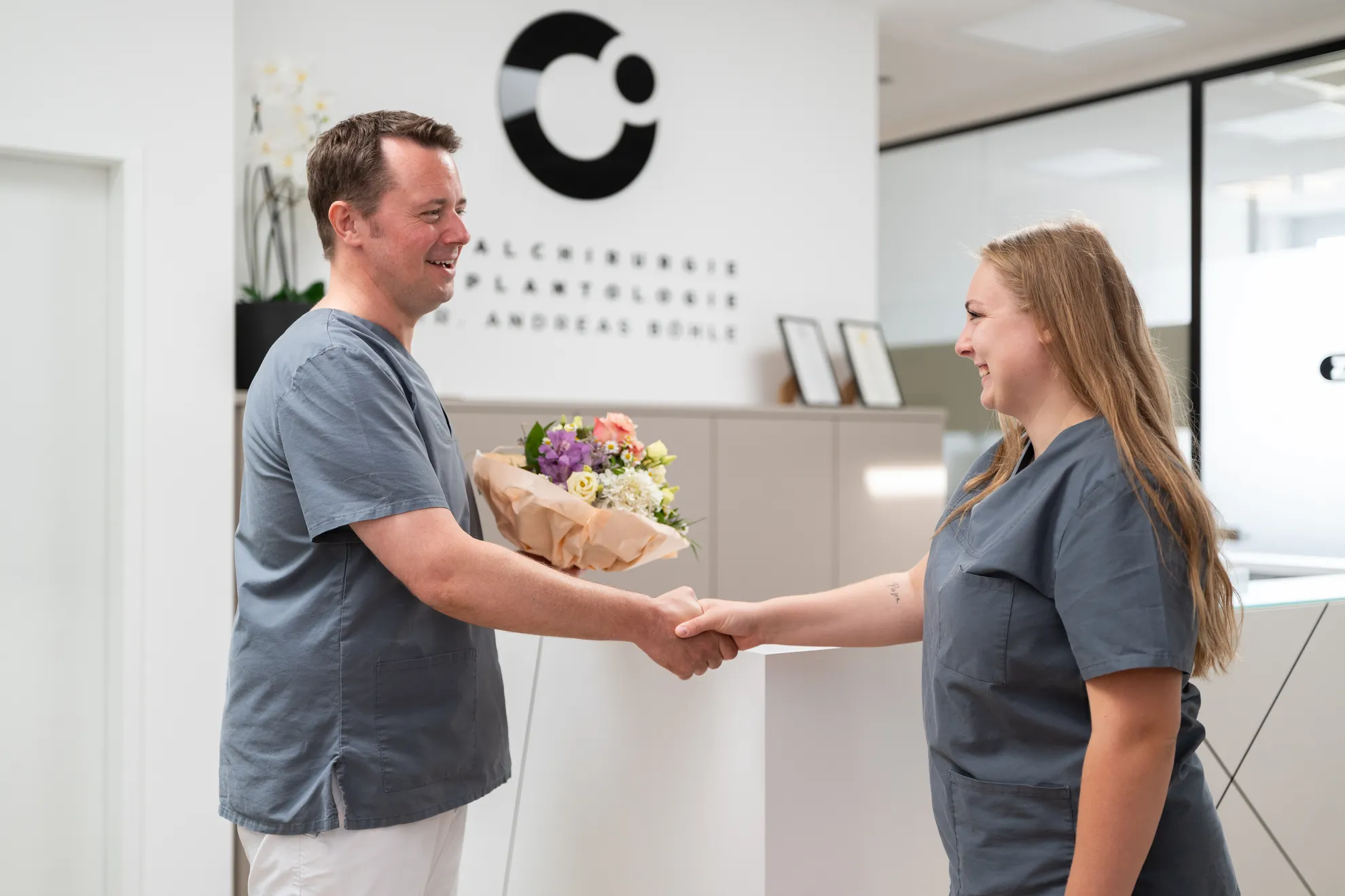 Übergabe von einem Blumenstrauß an Kollegin am Empfang vom Zahnarzt